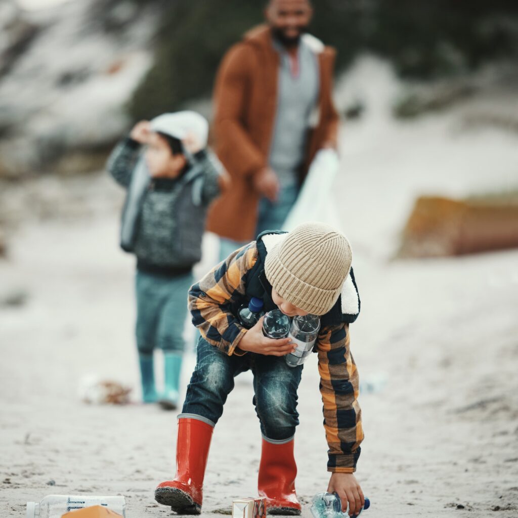 Beach clean, plastic and pollution with a child cleaning the environment for dirt or bottle on sand